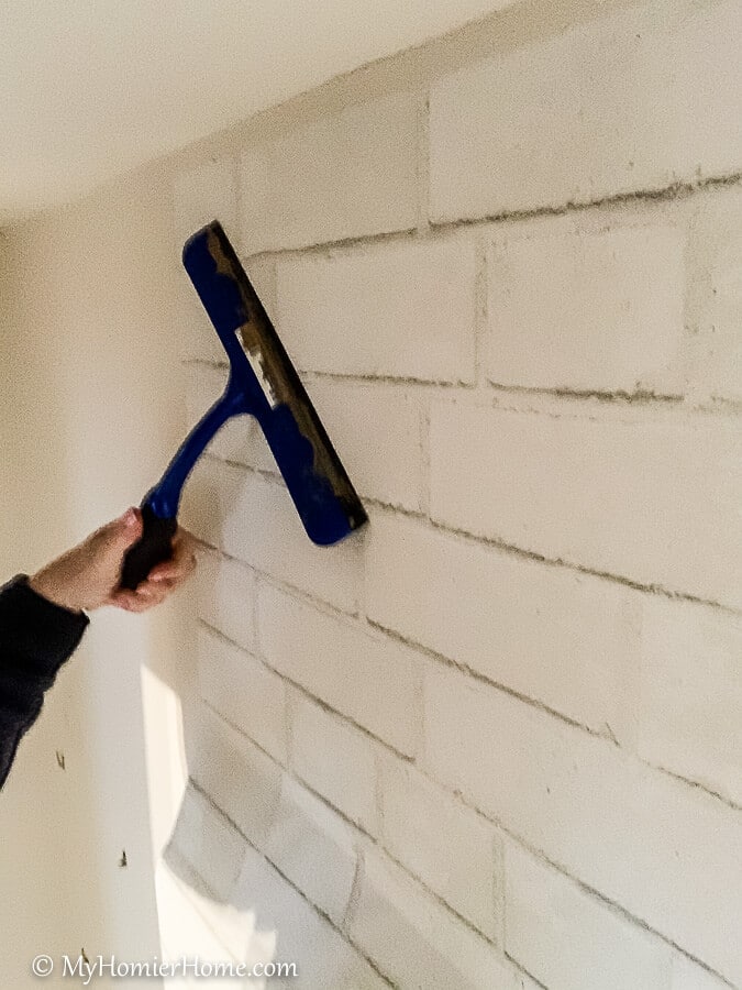 how to hang peel and stick wallpaper-13 Squeegee the peel and stick wallpaper from the center out, smoothing it and pulling the backing off as you go down.